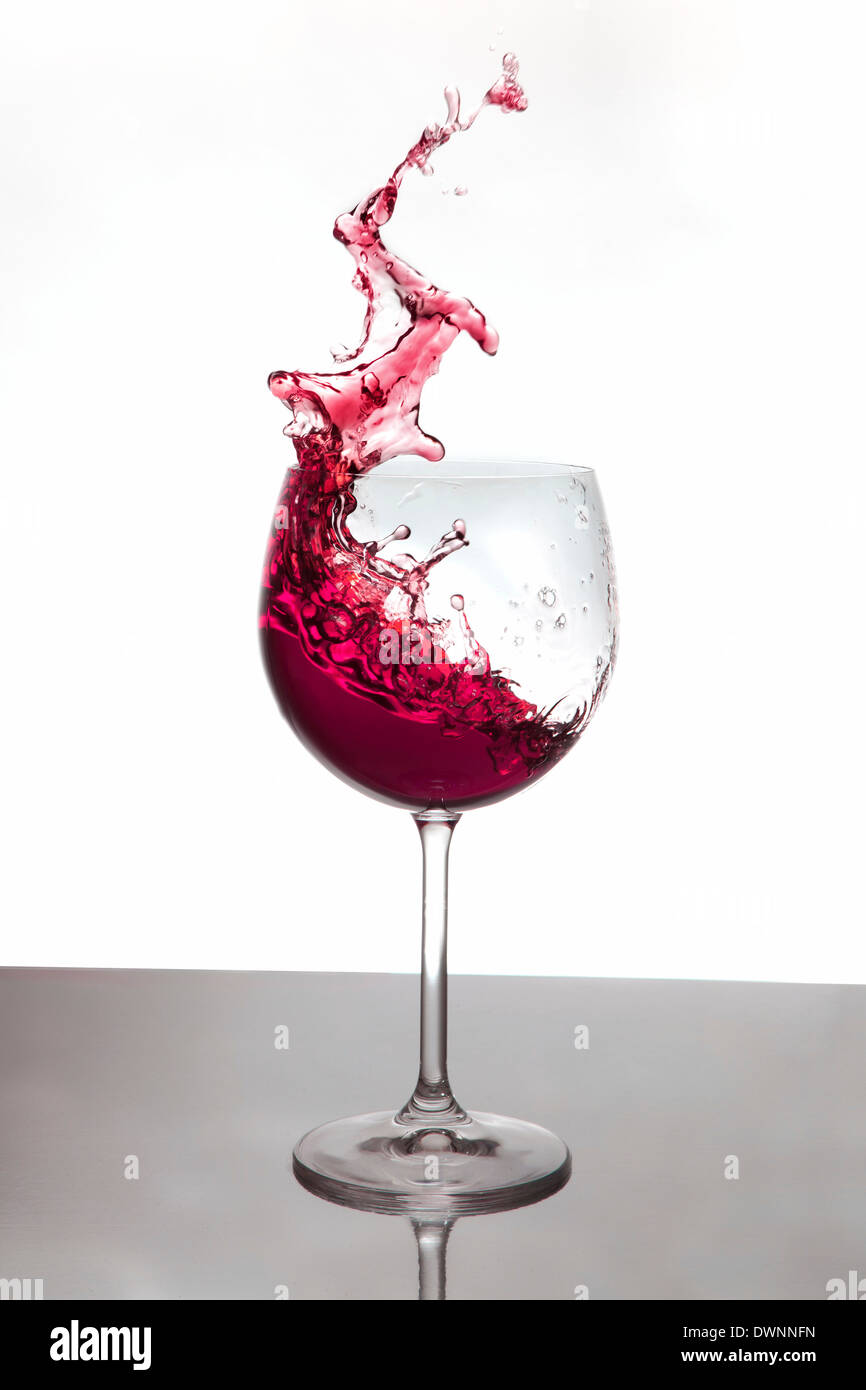 Red wine splashing out of a red wine glass Stock Photo