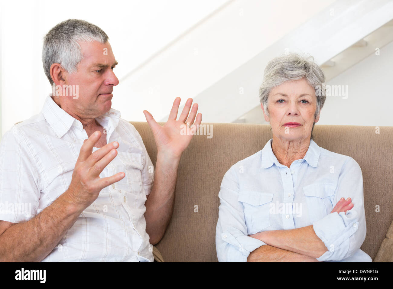 Senior couple sitting on couch having an argument Stock Photo