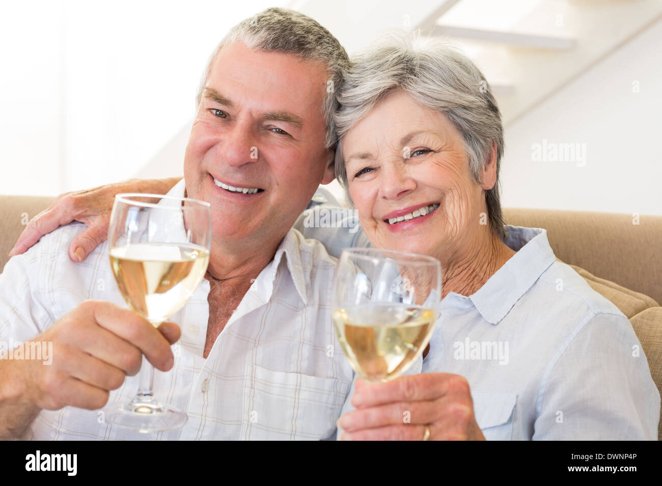 Senior couple sitting on couch having white wine Stock Photo