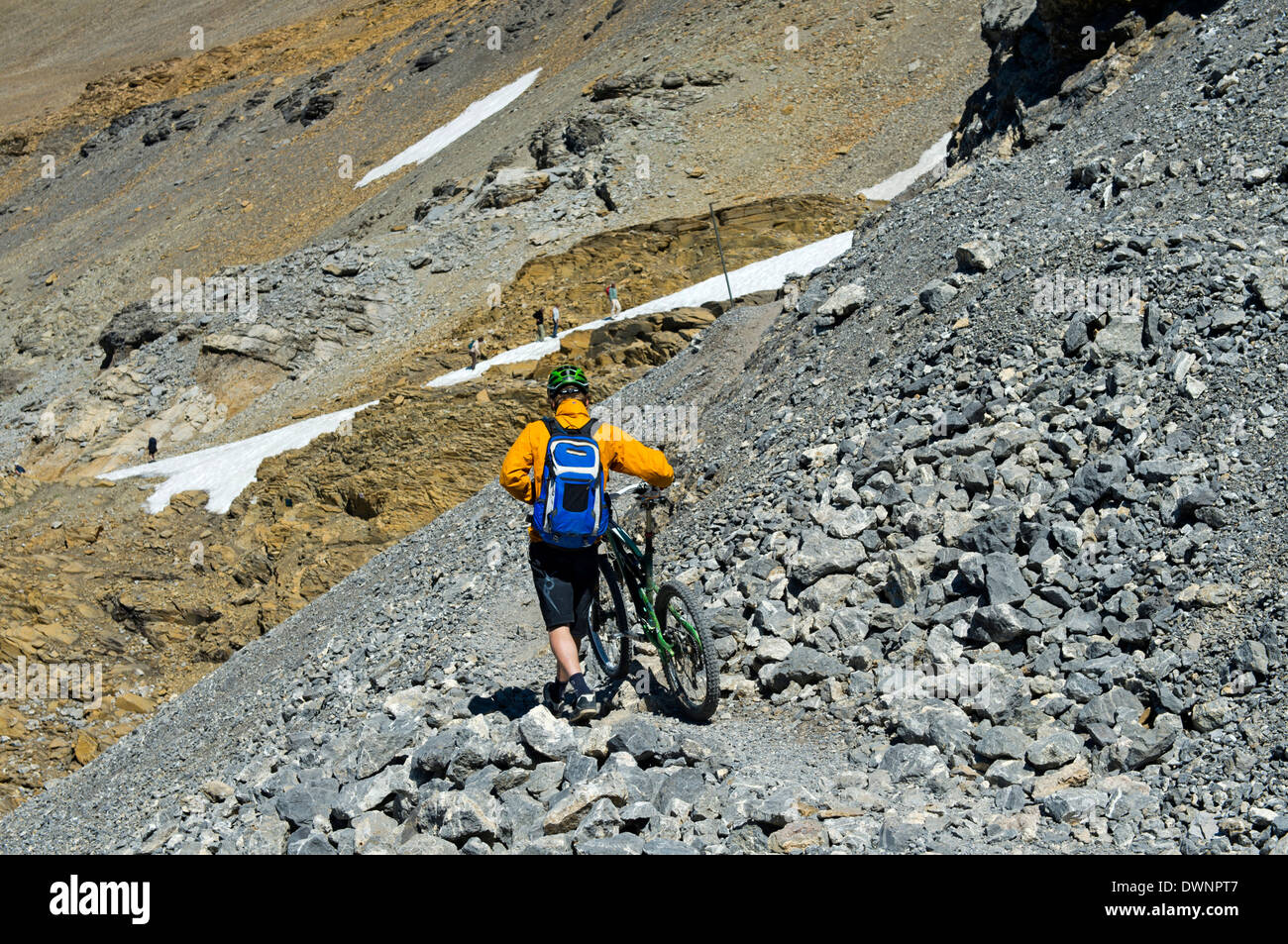 Mountain biker pushing his bike on a single trail in rocky terrain, Bernese Alps, Switzerland Stock Photo
