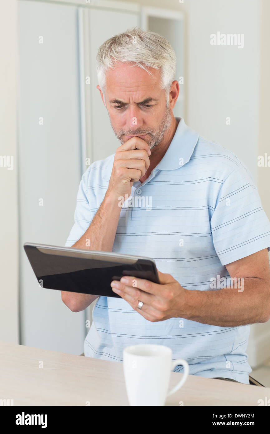Thoughtful man using his tablet at breakfast Stock Photo