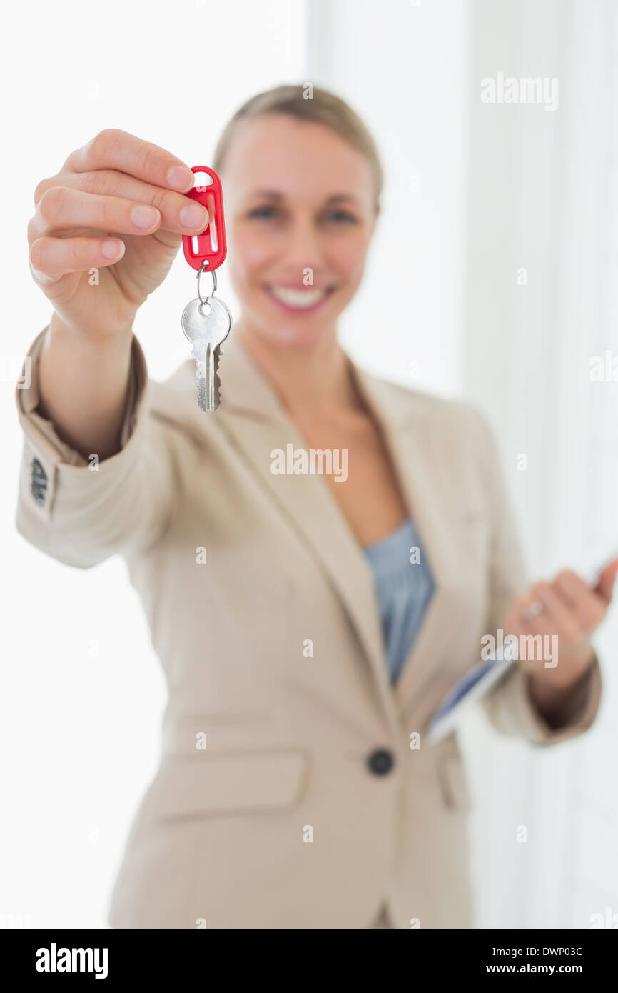 Smiling estate agent showing keys to camera Stock Photo - Alamy