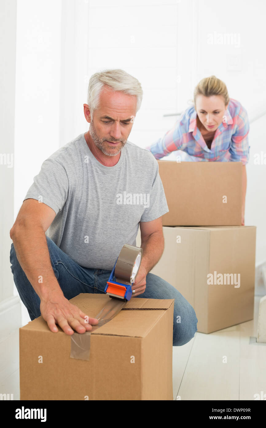 Happy couple sealing cardboard moving boxes Stock Photo Alamy
