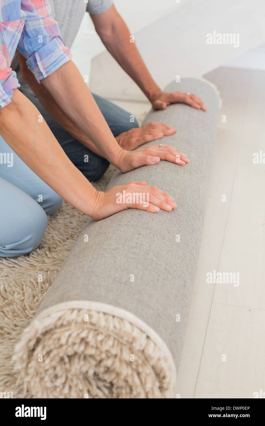 Couple rolling out new rug Stock Photo Alamy