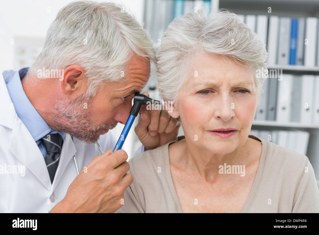 Doctor examining senior patient's ear hires stock photography and