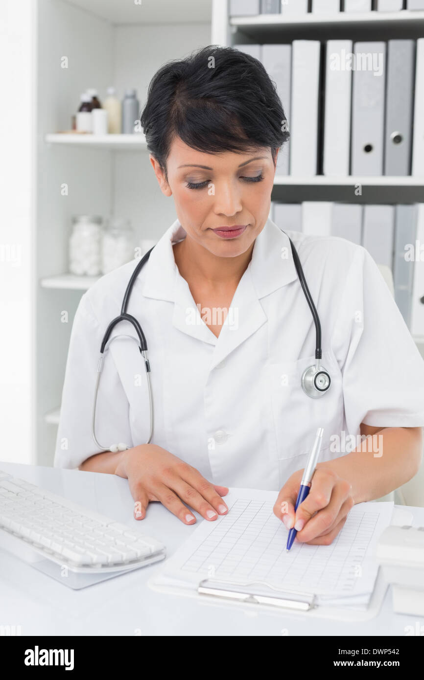 Concentrated female doctor writing on clipboard Stock Photo - Alamy