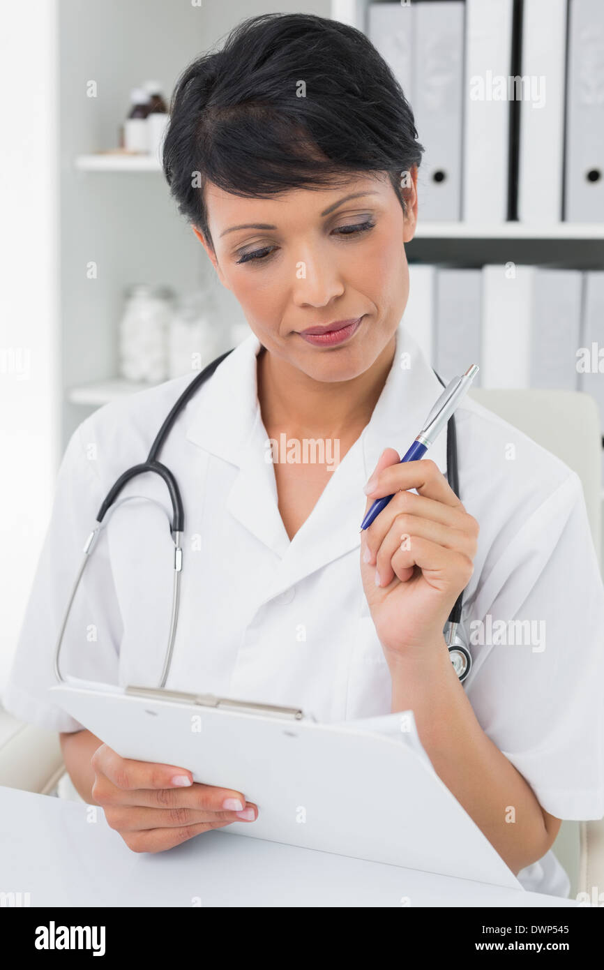 Concentrated female doctor writing on clipboard Stock Photo - Alamy