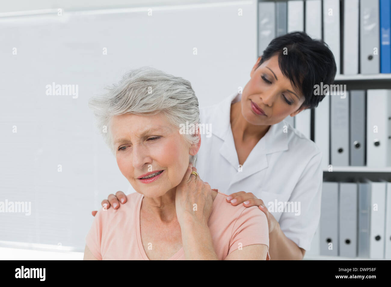 Chiropractor looking at senior woman with neck pain Stock Photo