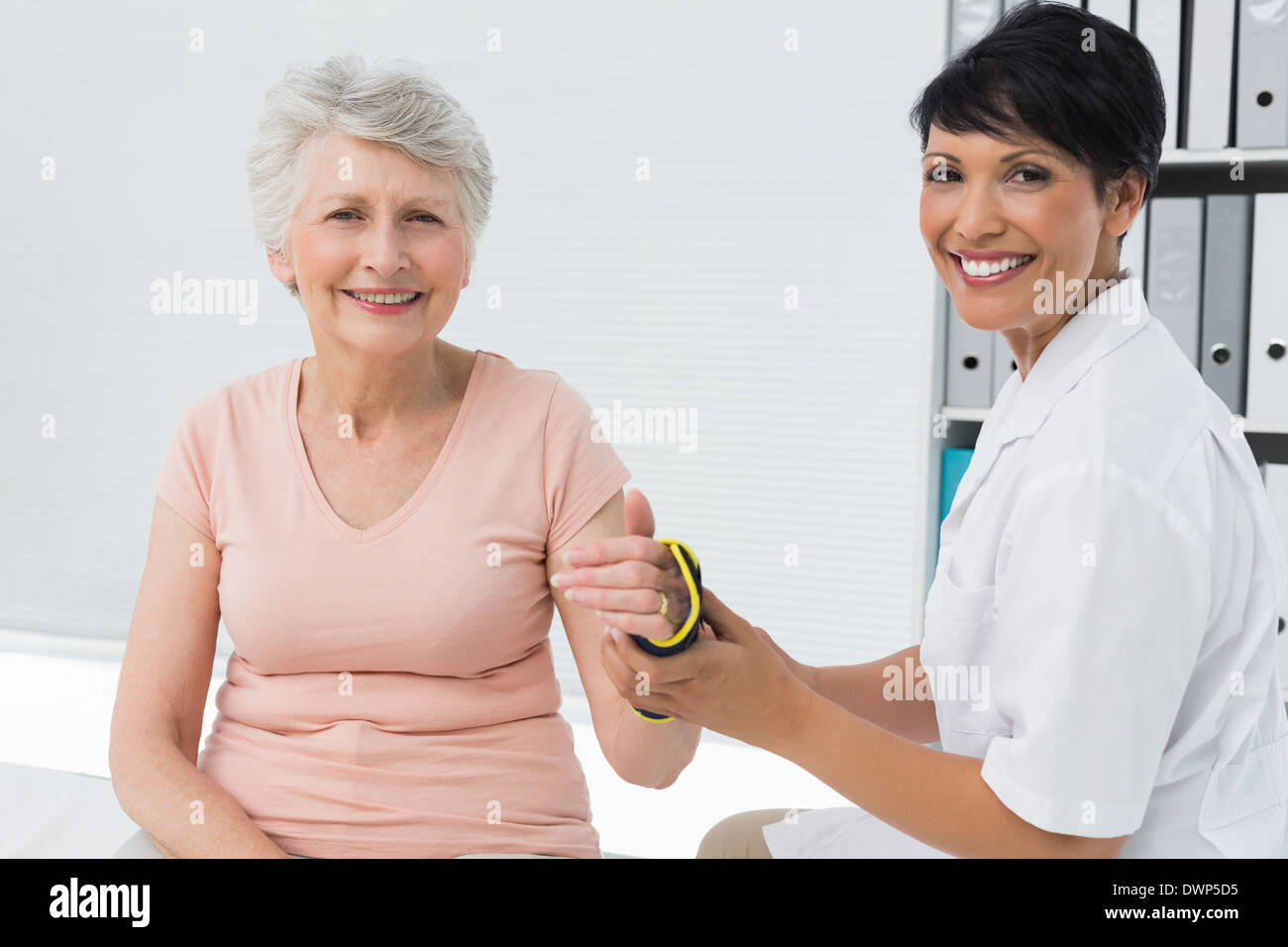 Female doctor fixing wrist brace on senior patients hand Stock Photo
