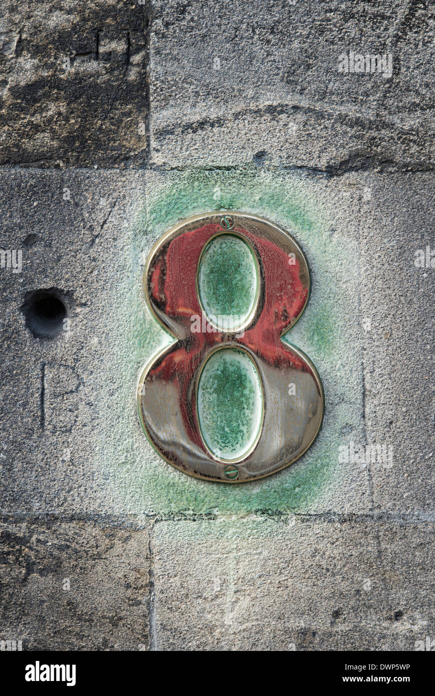 Copper number eight on a stone wall. Burford, Cotswolds, Oxfordshire, England Stock Photo