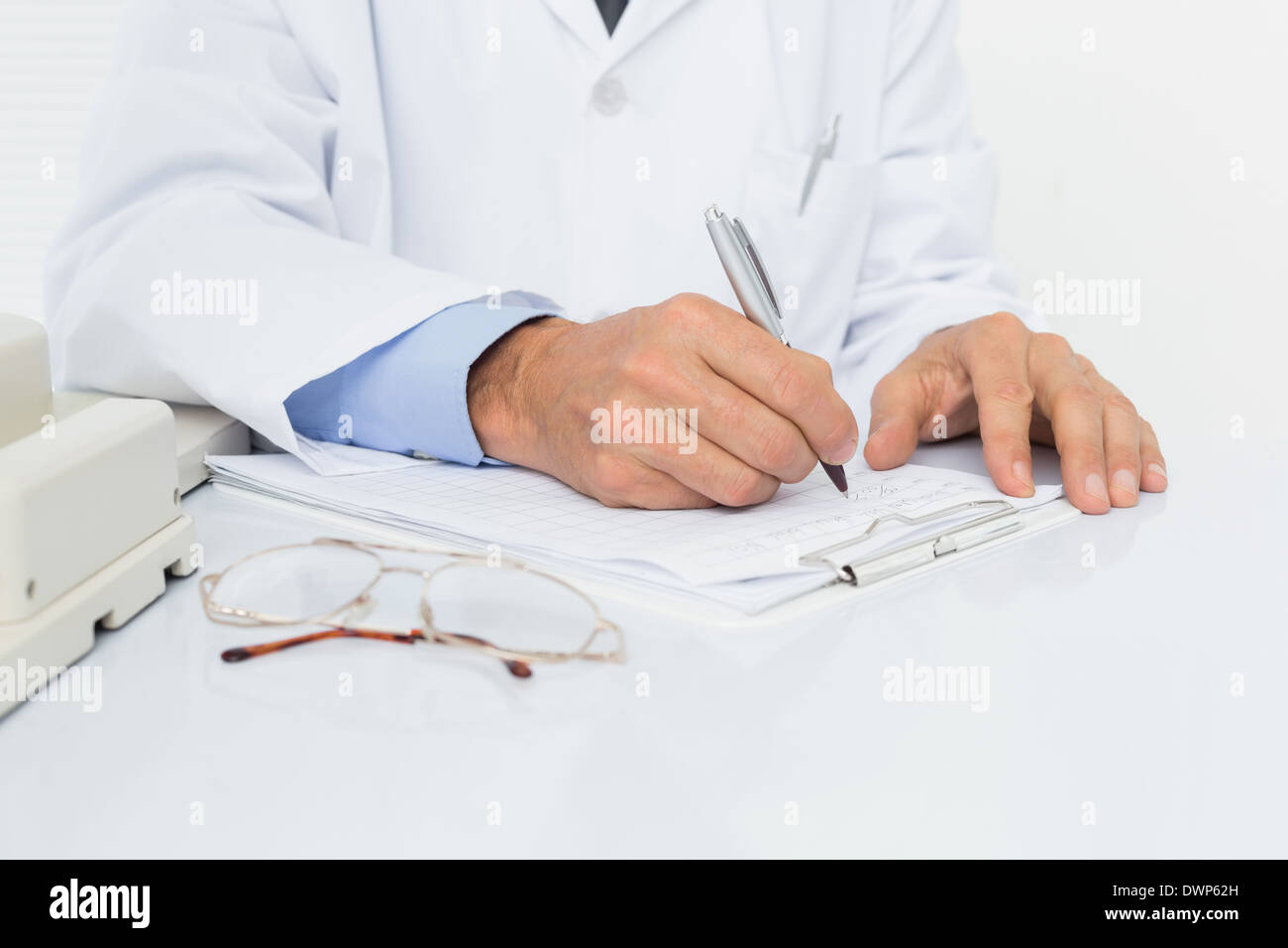 Mid section of a male doctor writing reports Stock Photo
