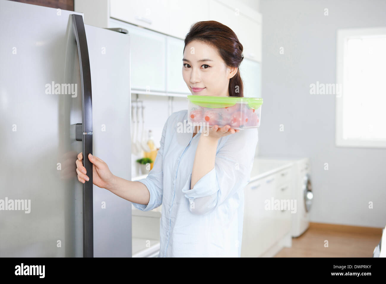 a woman taking out food from refrigerator in the kitchen Stock Photo