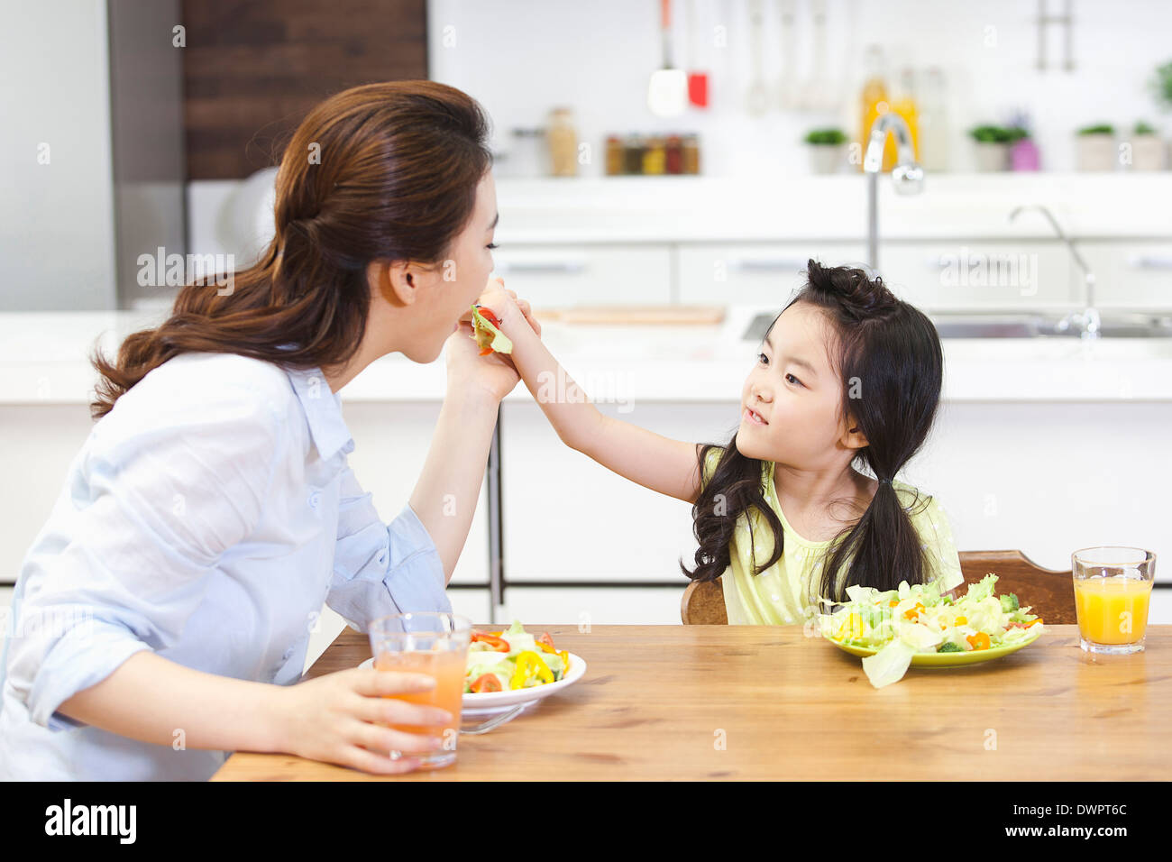 a kid giving a bite of sandwich to a woman Stock Photo