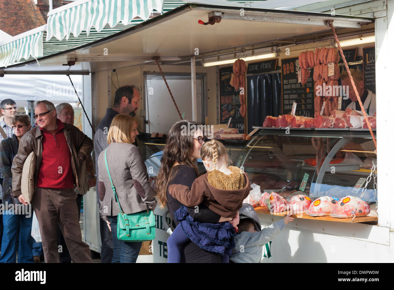 Customers buying meat from Butcher's van in Market. Stock Photo