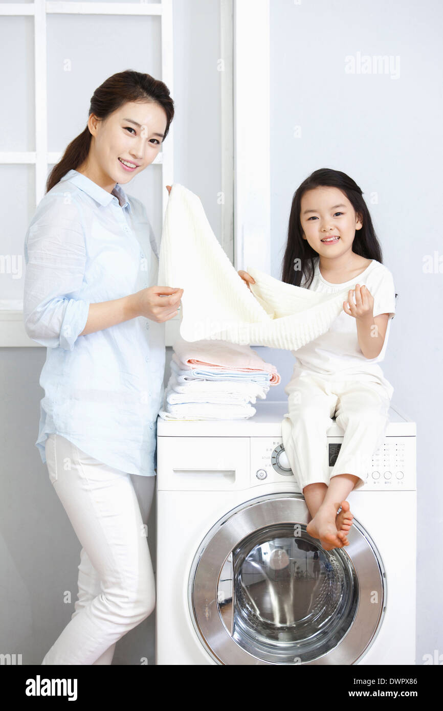 a woman and a daughter posing at washing machine Stock Photo