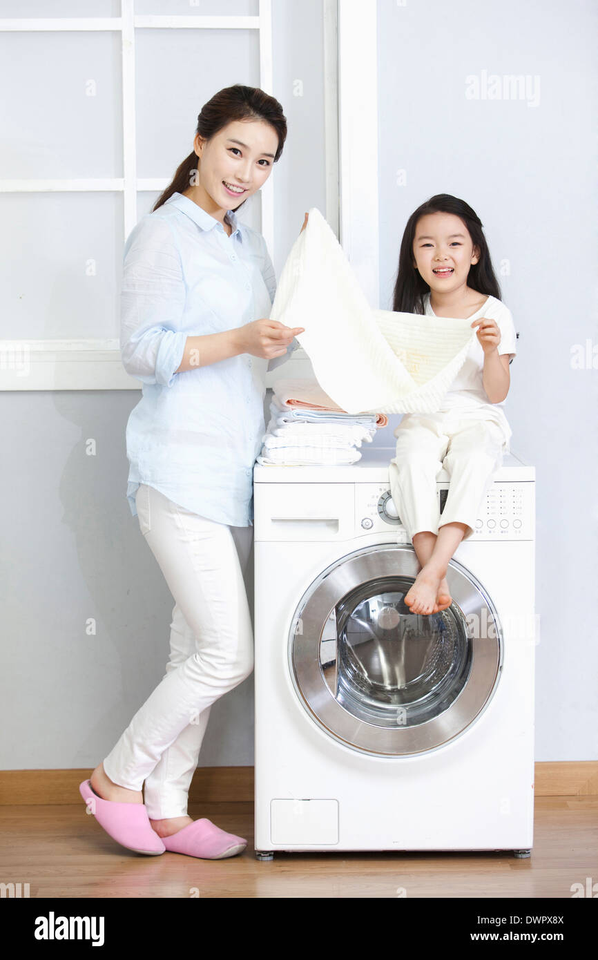 a woman and a daughter posing at washing machine Stock Photo