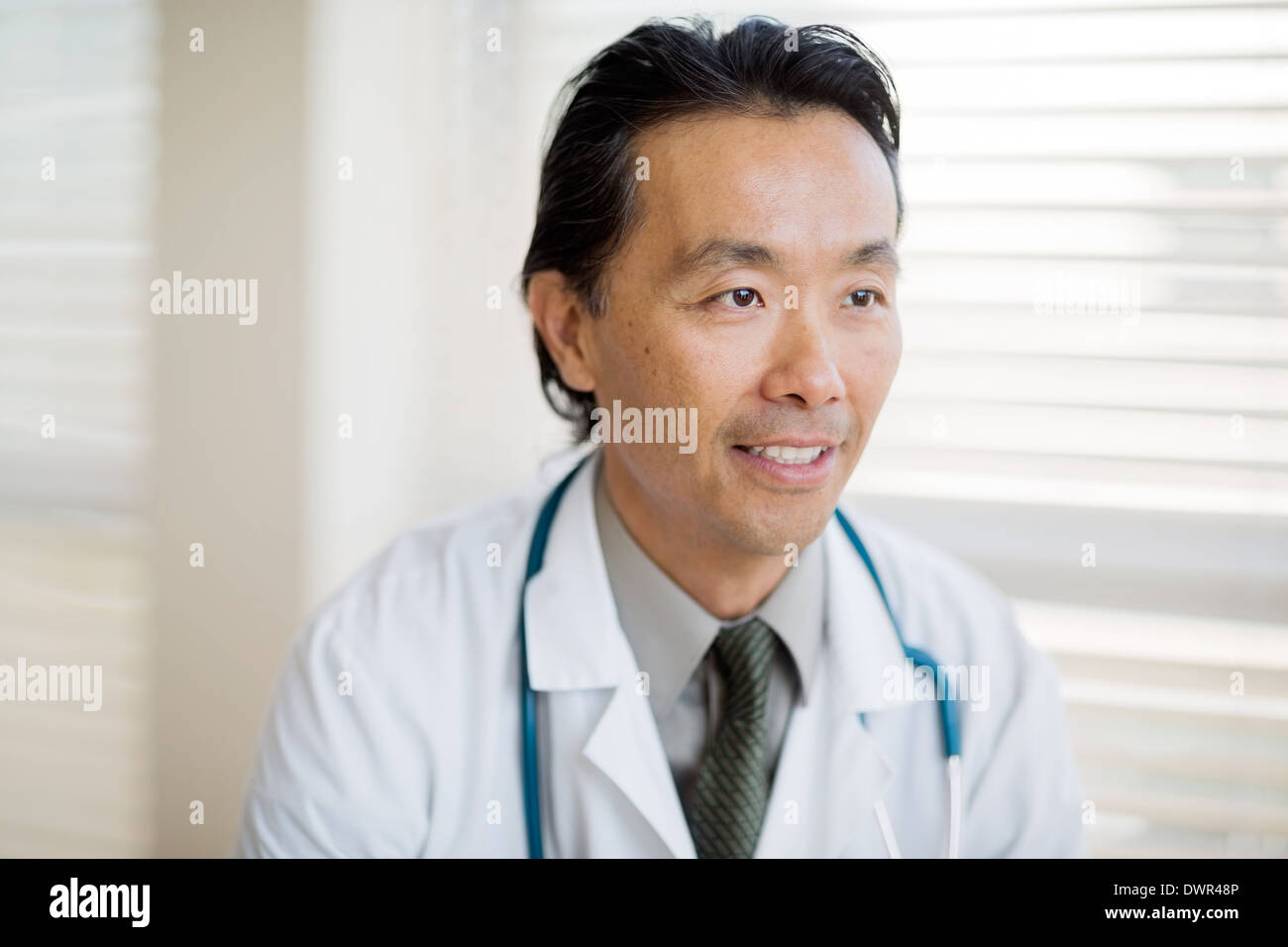 Thoughtful Doctor Smiling In Clinic Stock Photo