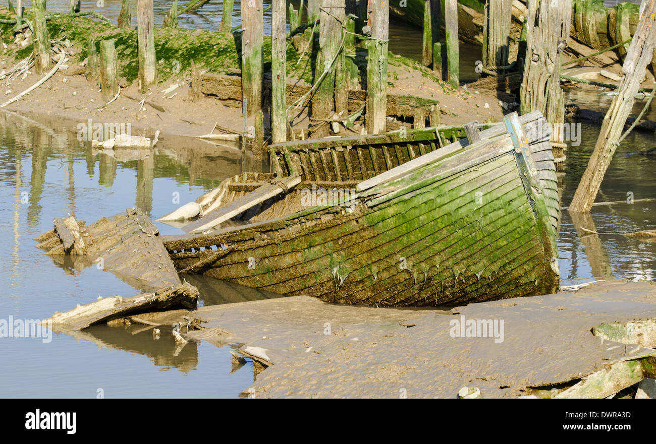 A small wrecked wooden rowing boat. Decaying rowing boat made of wood, stuck in mud. Stock Photo