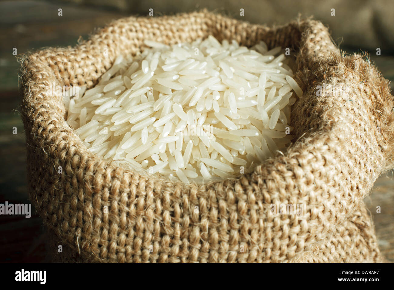 White uncooked basmati rice in burlap bag Stock Photo