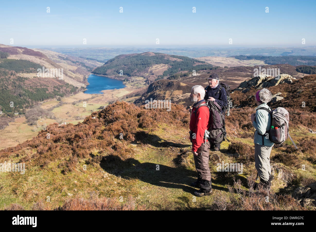 Three walkers on Crimpiau hilltop with a view to Llyn Crafnant lake in valley in Snowdonia National Park, Conwy, North Wales, UK, Britain Stock Photo