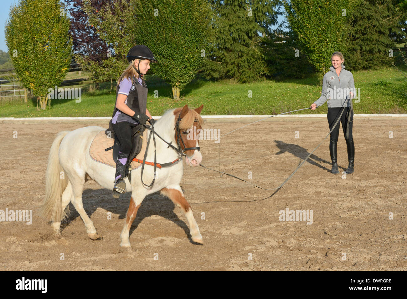 Girl wearing a body protector having a lunge lesson on a pony trotting