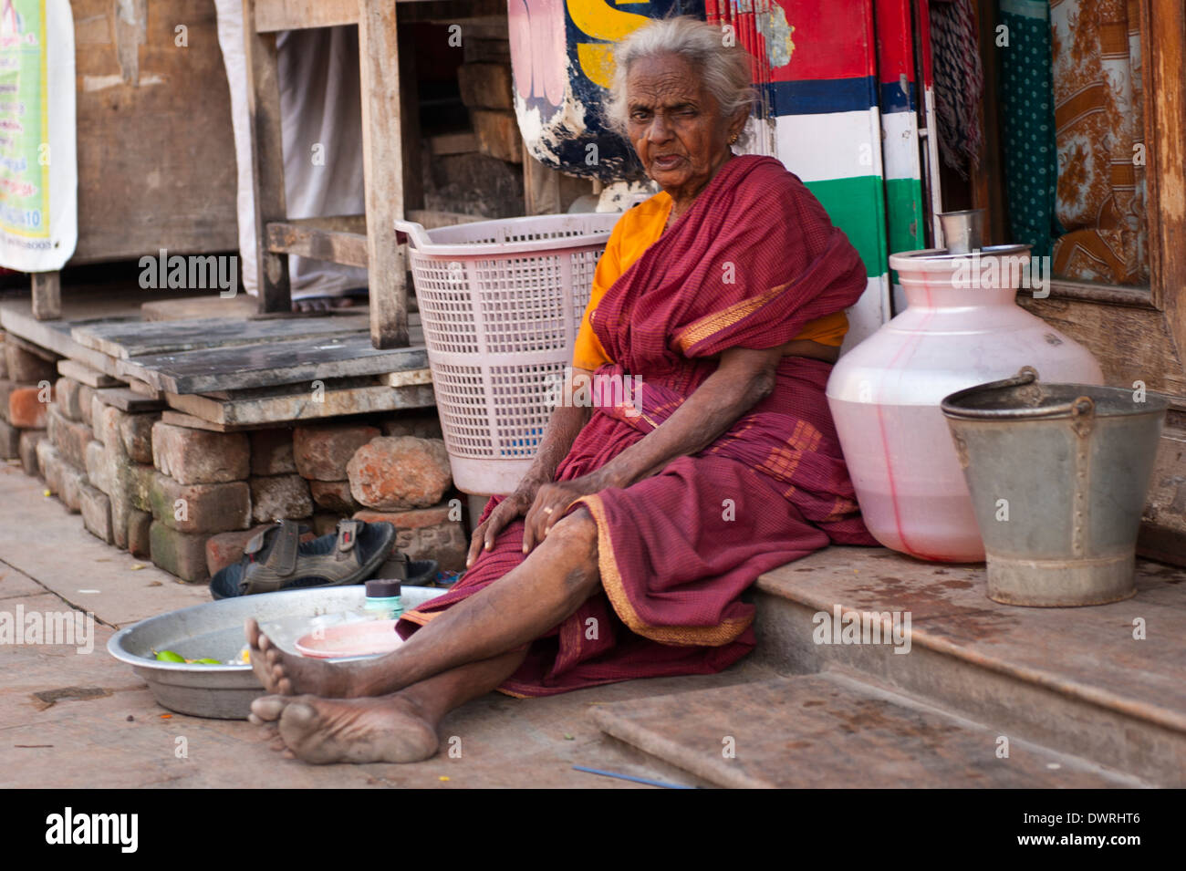 South Southern India Tamil Nadu Madurai street scene grey gray hair old wrinkled woman lady female sitting on step sells fruit Stock Photo