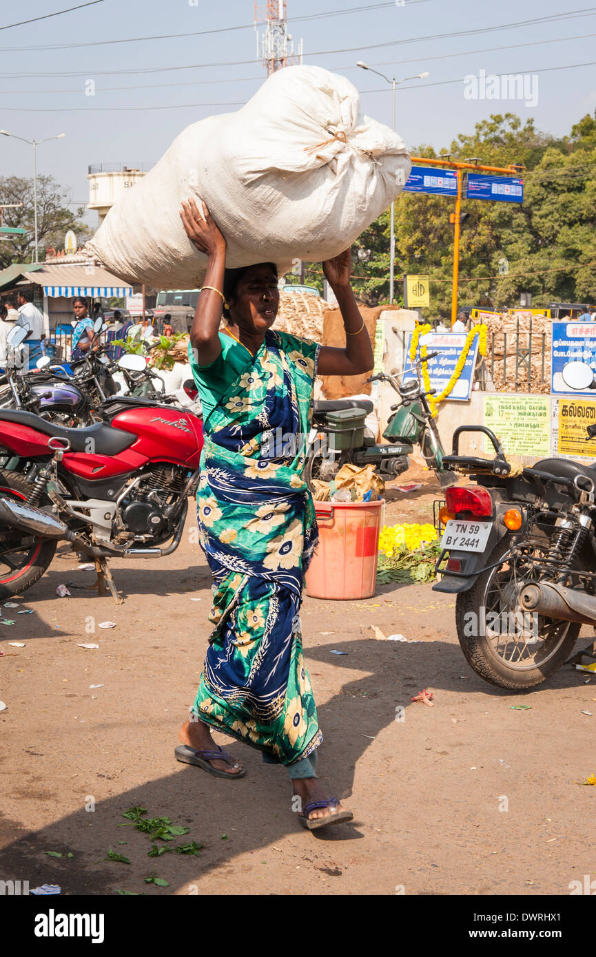 South Southern India Tamil Nadu Madurai flower market woman lady female in green sari saree carries white sack on head Stock Photo