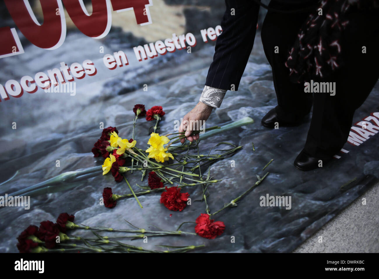 Madrid, Spain. 11th Mar, 2014. A woman drops flowers during an event outside Atocha's train station in remember of the people killed in the Madrid train bombings in Madrid, Spain, Tuesday March 11, 2014, in remembrance of those killed and injured in the Madrid train bombings, marking the 10th anniversary of Europe's worst Islamic terror attack. The attackers targeted four commuter trains with 10 shrapnel-filled bombs concealed in backpacks during morning rush hour on March 11, 2004. Credit:  Rodrigo Garcia/NurPhoto/ZUMAPRESS.com/Alamy Live News Stock Photo