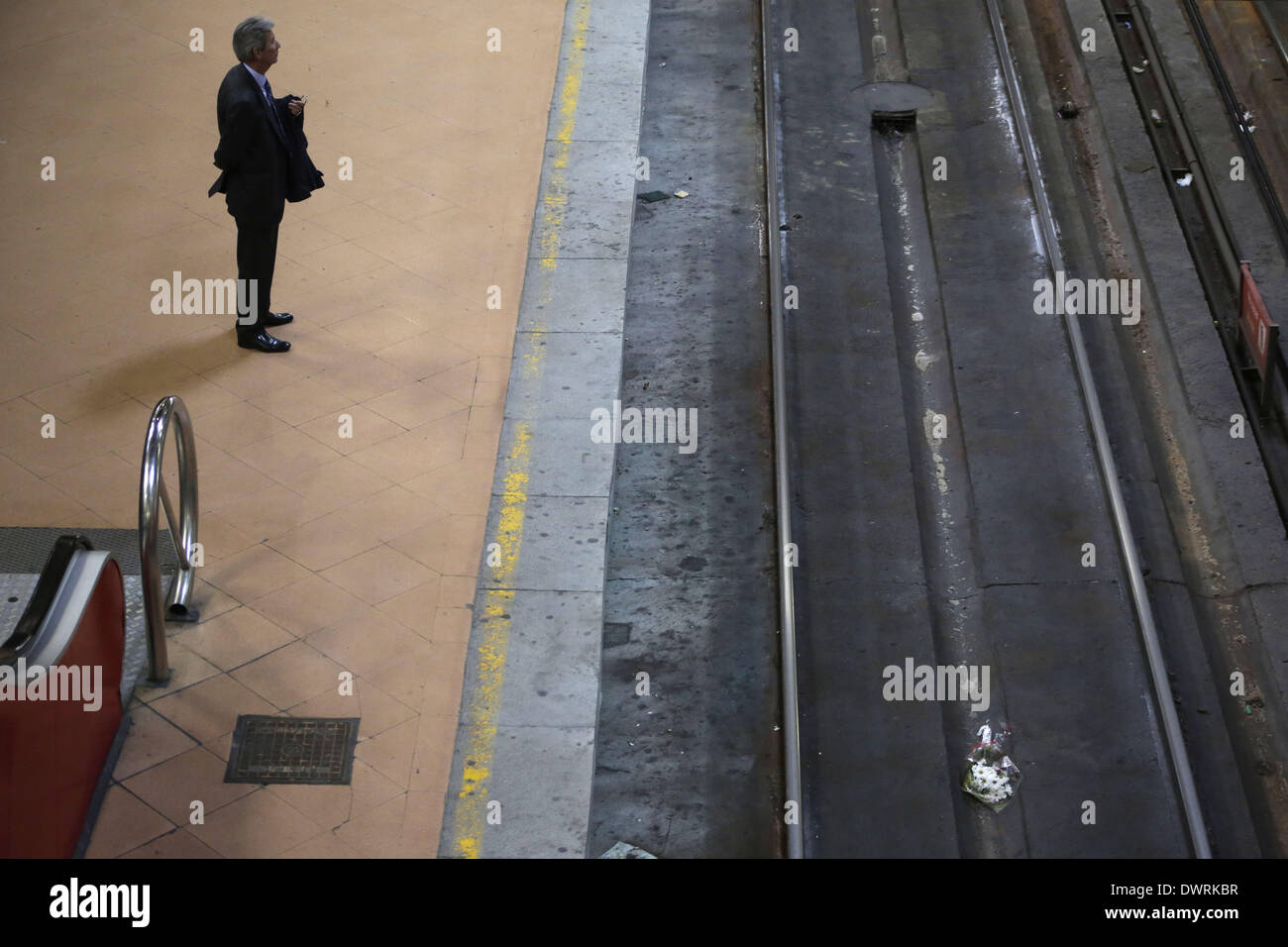 Madrid, Spain. 11th Mar, 2014. A man waits for the train on the second platform at the Atocha train station while a bouquet lies on the railway track in Madrid, Spain, Tuesday March 11, 2014, in remembrance of those killed and injured in the Madrid train bombings, marking the 10th anniversary of Europe's worst Islamic terror attack. The attackers targeted four commuter trains with 10 shrapnel-filled bombs concealed in backpacks during morning rush hour on March 11, 2004. Credit:  Rodrigo Garcia/NurPhoto/ZUMAPRESS.com/Alamy Live News Stock Photo