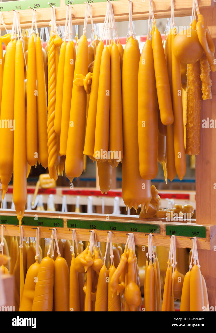 A variety of handmade candles of beeswax are hanging off the shelf in a chandler's workshop. Stock Photo