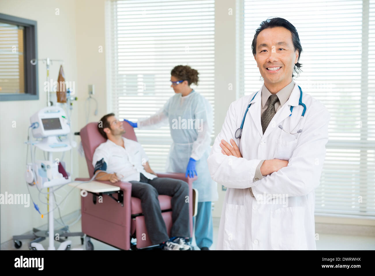 Happy Doctor With Patient Being Examined By Heartbeat Machine Stock Photo