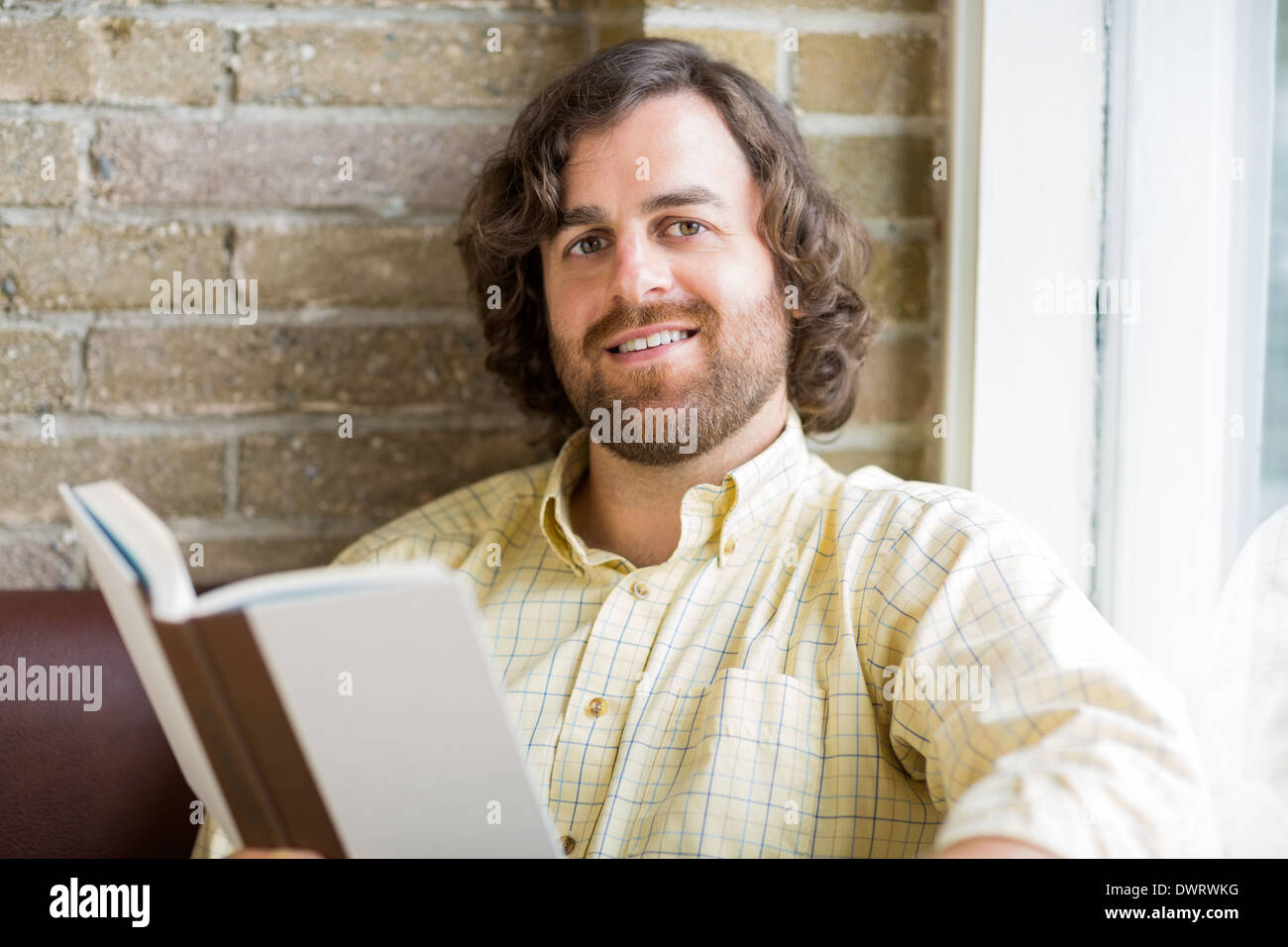 Man With Book In Coffeeshop Stock Photo