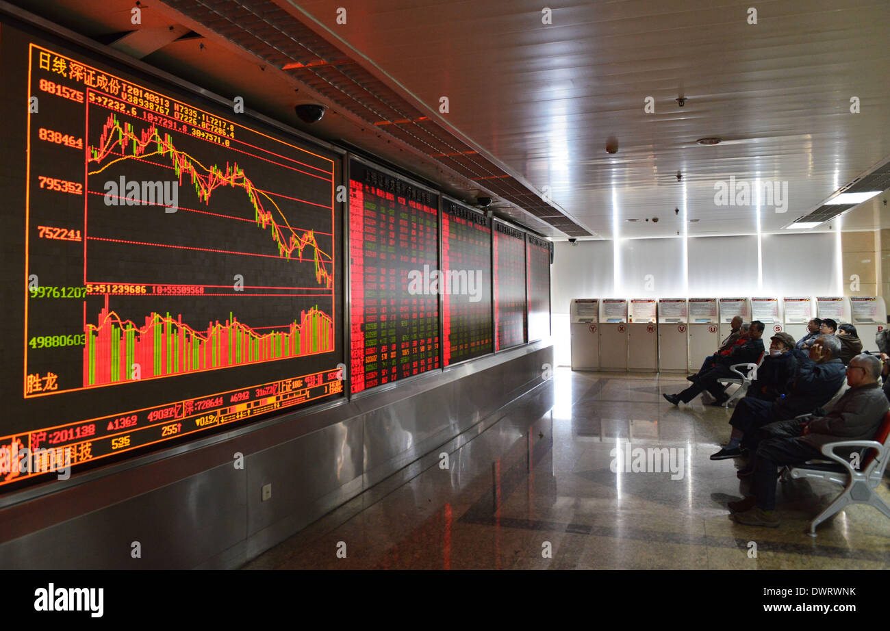 Beijing, China. 13th Mar, 2014. Investors look through stock information in a trading hall at a securities firm in Beijing, capital of China, March 13, 2014. Chinese shares closed higher on March 13 with the benchmark Shanghai Composite Index up 1.07 percent, or 21.42 points, to finish at 2,019.11. The Shenzhen Component Index slightly gained 1.42 percent, or 102.27 points, to close at 7,319.29. © Wang Quanchao/Xinhua/Alamy Live News Stock Photo