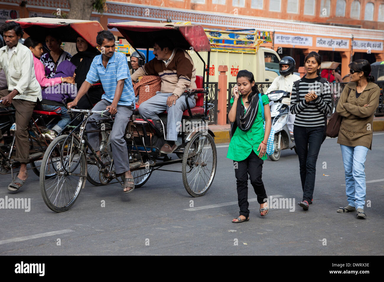 Jaipur, Rajasthan, India. Street Traffic; Women Crossing the Street, Passengers Riding Rickshaws. Stock Photo