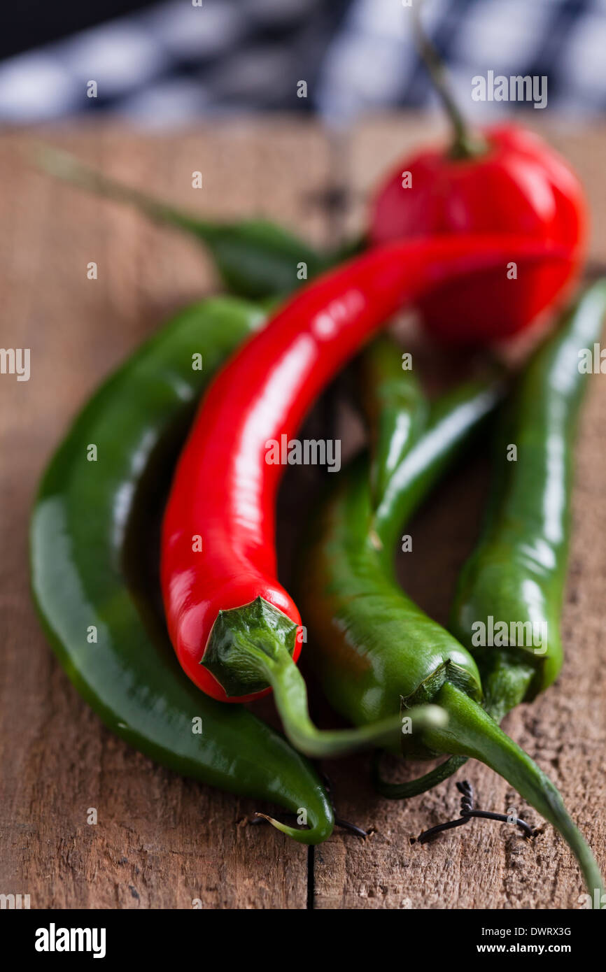 Closeup of red and green chili peppers on wooden board surface Stock Photo
