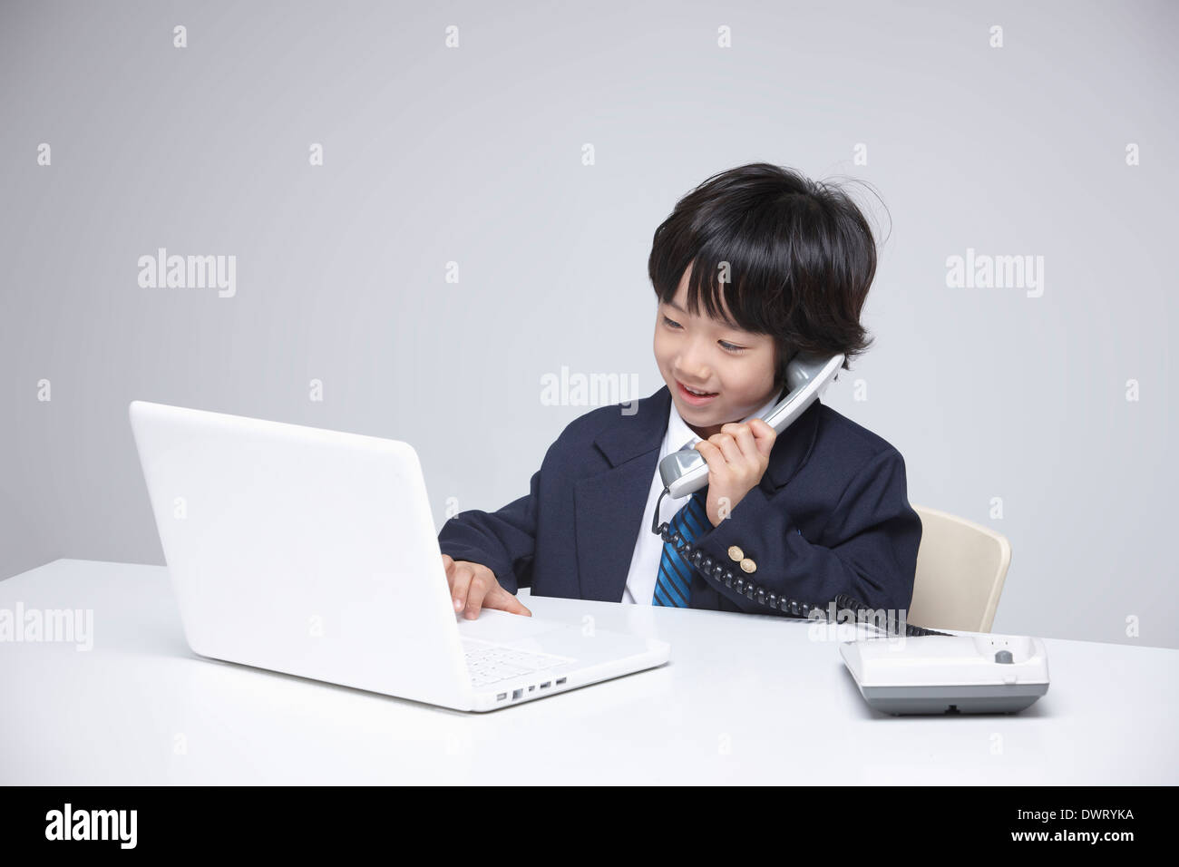 a kid wearing a business suit using a laptop Stock Photo