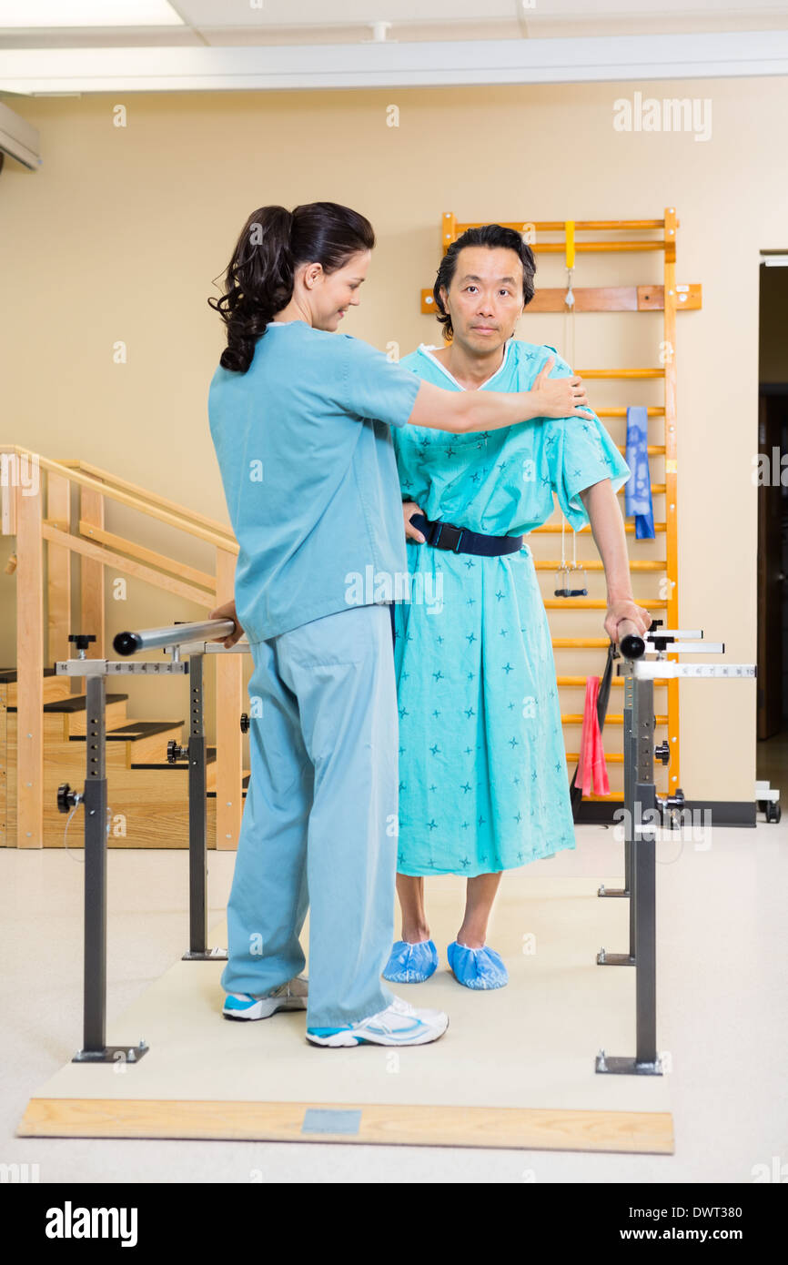Physical Therapist Assisting Male Patient In Walking Stock Photo