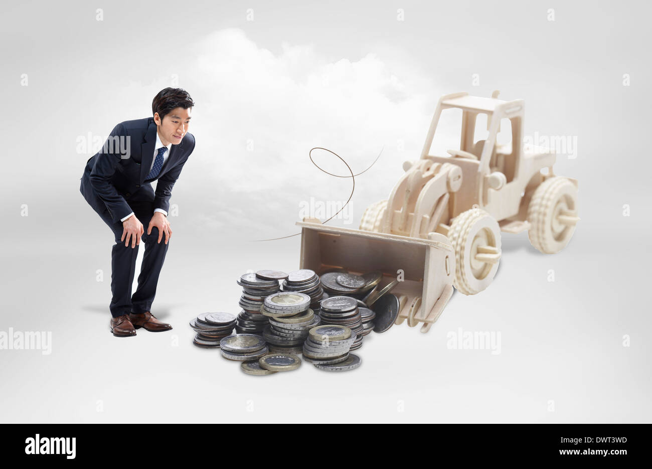 a business man looking at a pile of coins Stock Photo