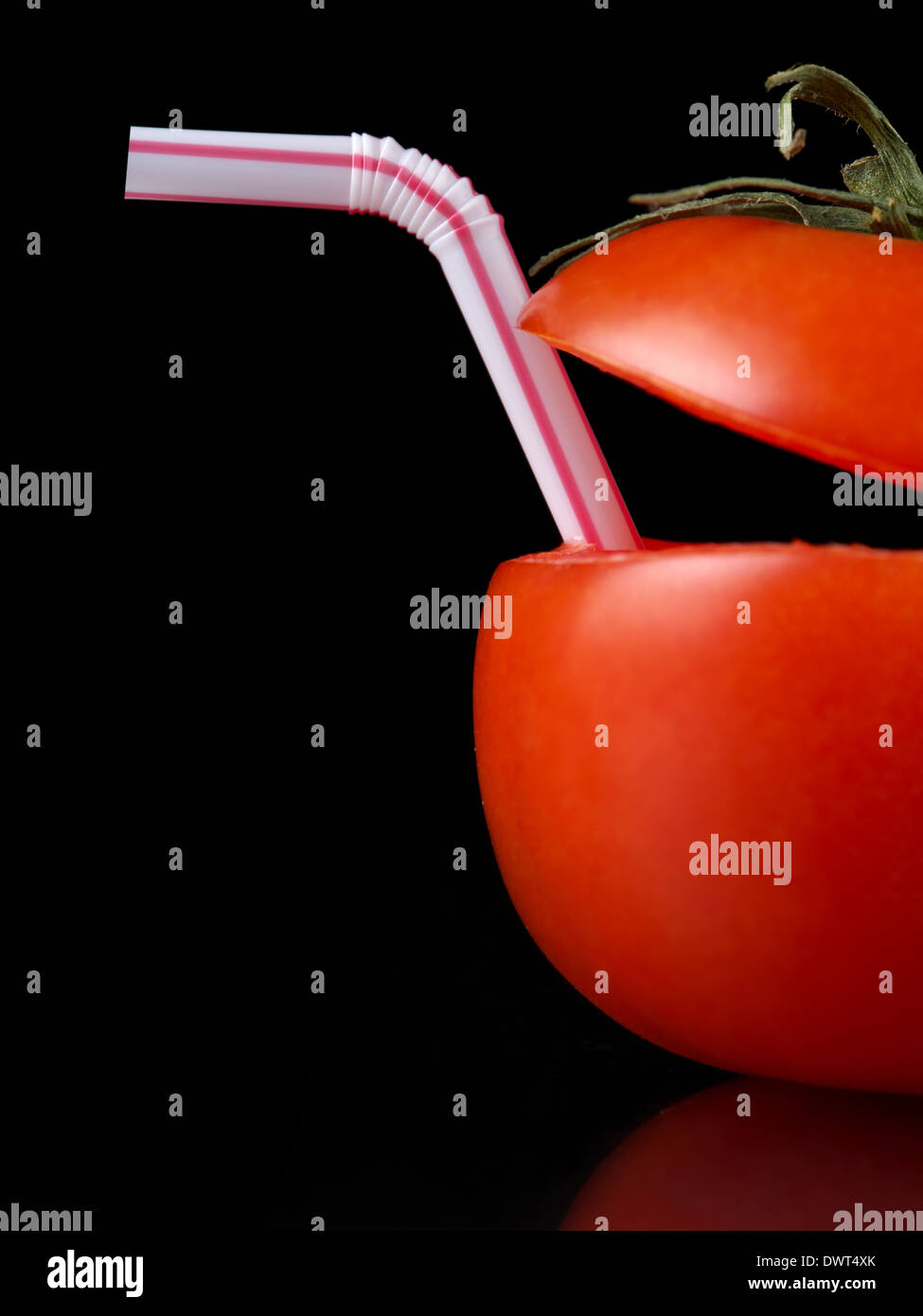 Tomato with straw as natural cocktail shot on black Stock Photo