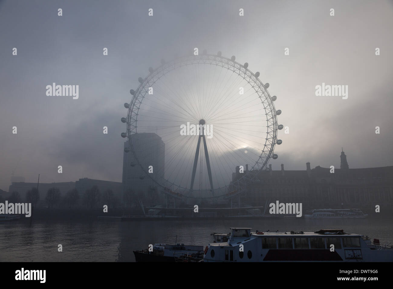 LONDON, UK, 13th Mar, 2014. London starts the day swathed in a blanket of fog. The sun rises above County Hall, Westminster, and behind the London Eye Credit:  Steve Bright/Alamy Live News Stock Photo