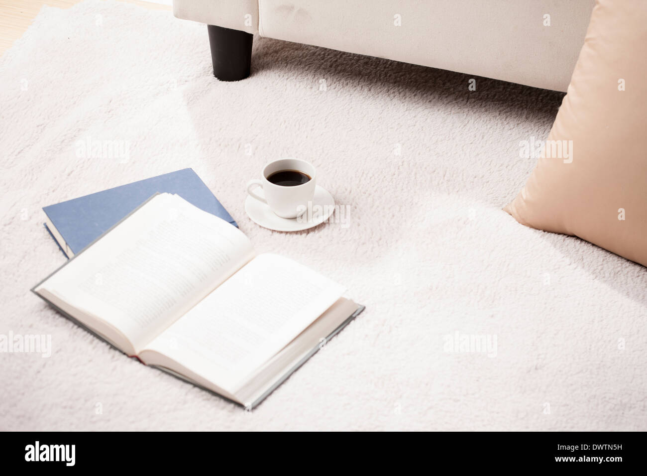 an open book and a cup on the floor Stock Photo