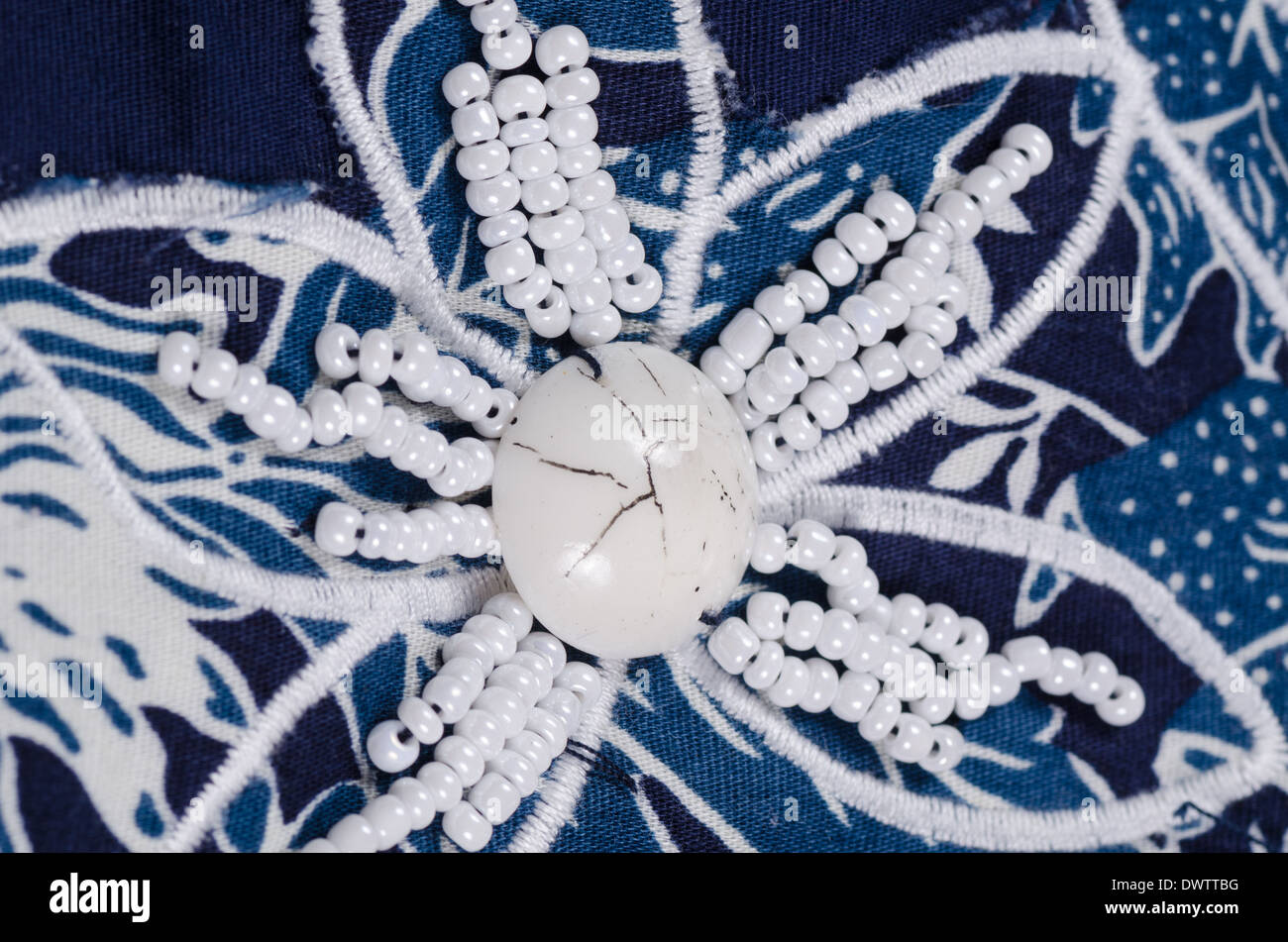 Embroidered flower shaped bead pattern on blue fabric Stock Photo