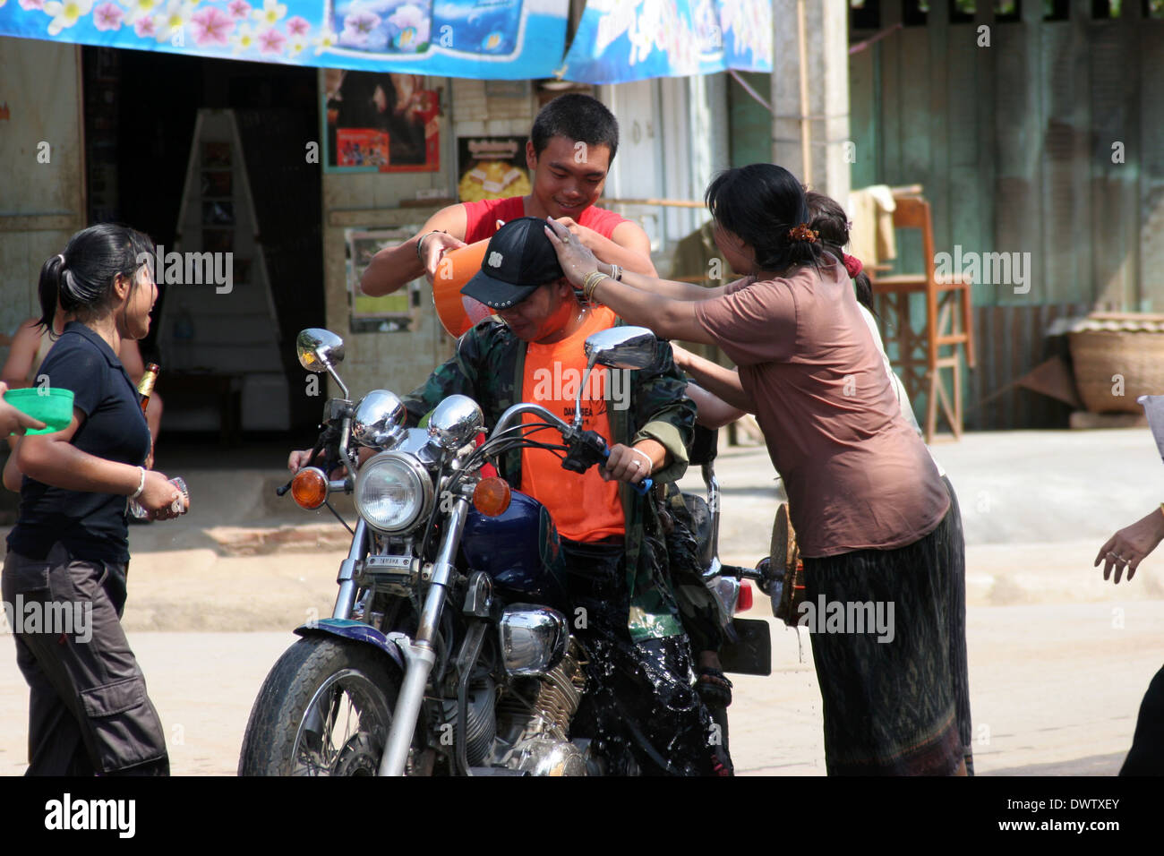 People are throwing water on a man riding a motorcycle at a Lao New