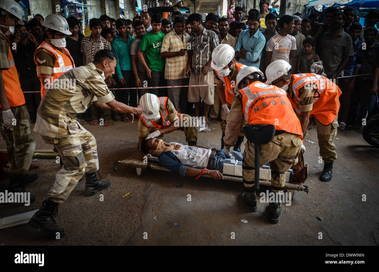 Dimapur, India. 13th Mar, 2014. Nagaland State Disaster Response Force (NSDRF) put a man in a stretcher pretending to be injured as onlookers watch during an earthquake mock drill in Dimapur, India north eastern state of Nagaland on Thursday, March 13, 2014. The entire north east India are exercising earthquake mock drill, also one of the biggest mock drill in South East Asia aiming to assess multi-state disaster preparedness, for the fear of 1897's 8.7 magnitude Shillong earthquake replication. Credit:  ZUMA Press, Inc./Alamy Live News Stock Photo