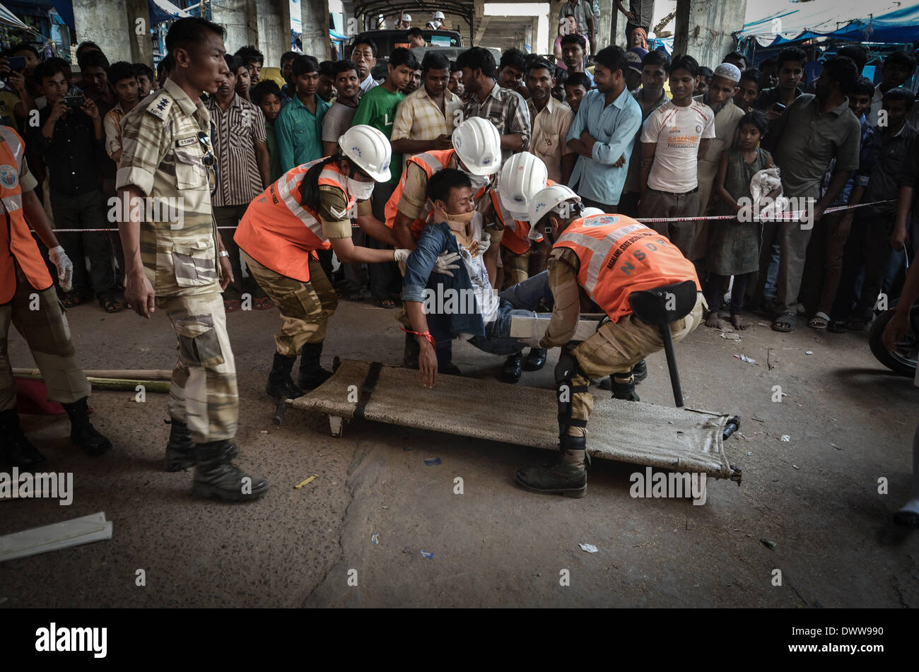 Dimapur, India. 13th Mar, 2014. Nagaland State Disaster Response Force (NSDRF) put a man in a stretcher pretending to be injured as onlookers watch during an earthquake mock drill in Dimapur, India north eastern state of Nagaland on Thursday, March 13, 2014. The entire north east India are exercising earthquake mock drill, also one of the biggest mock drill in South East Asia aiming to assess multi-state disaster preparedness, for the fear of 1897's 8.7 magnitude Shillong earthquake replication. Credit:  ZUMA Press, Inc./Alamy Live News Stock Photo