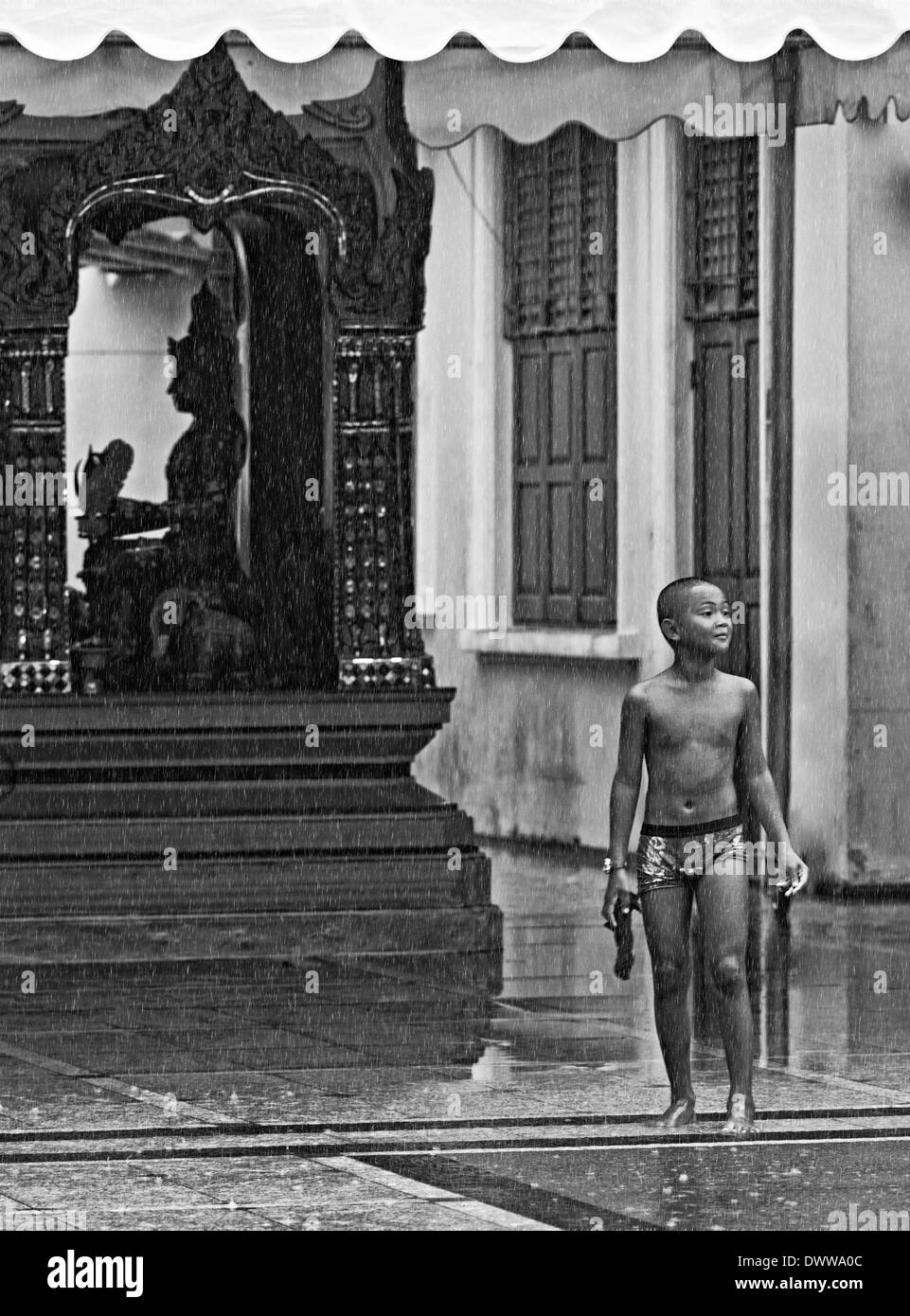 Unknown Burmese boy playing in the rain. Mandalay Burma Stock Photo