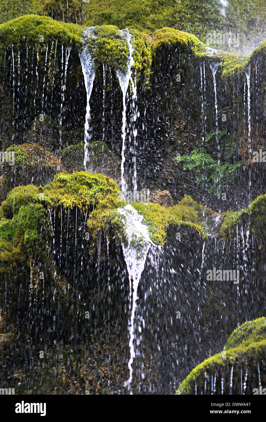 Falling jet of water on a background of a wall covered by a moss.  France, Provence Stock Photo