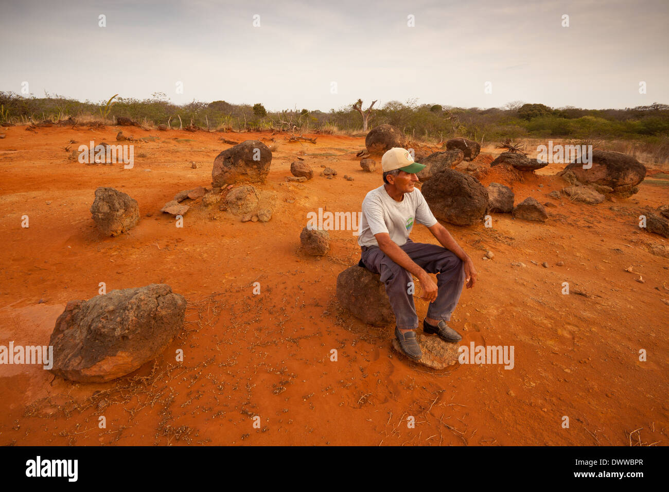 Panamanian man sits on one of the large volcanic stones in Sarigua national park, Herrera province, Republic of Panama. Stock Photo