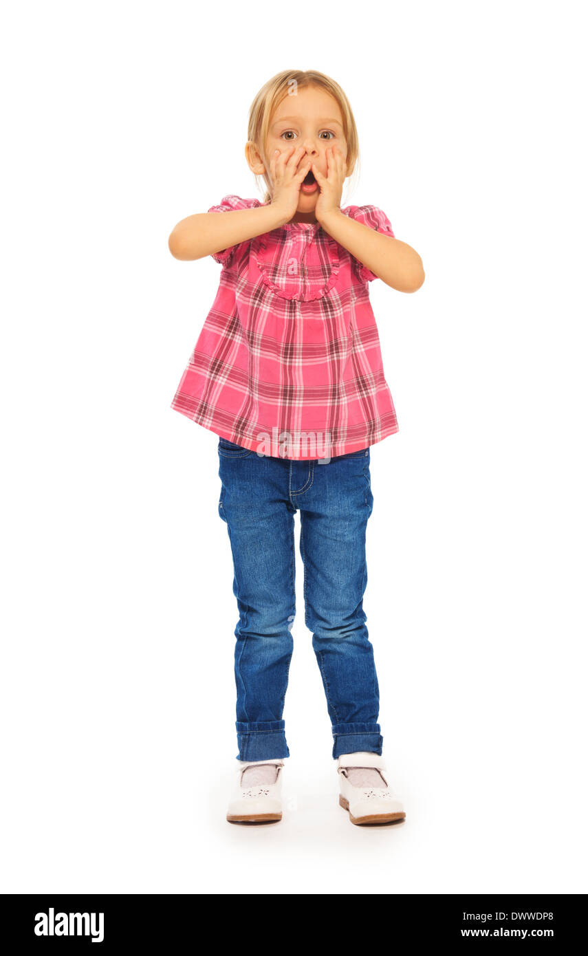 Full height portrait shocked little blond 4 years old girl holding face with hands Stock Photo