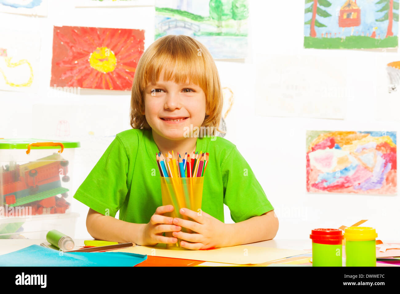 4 years old boy with pencils in the art class room with images on